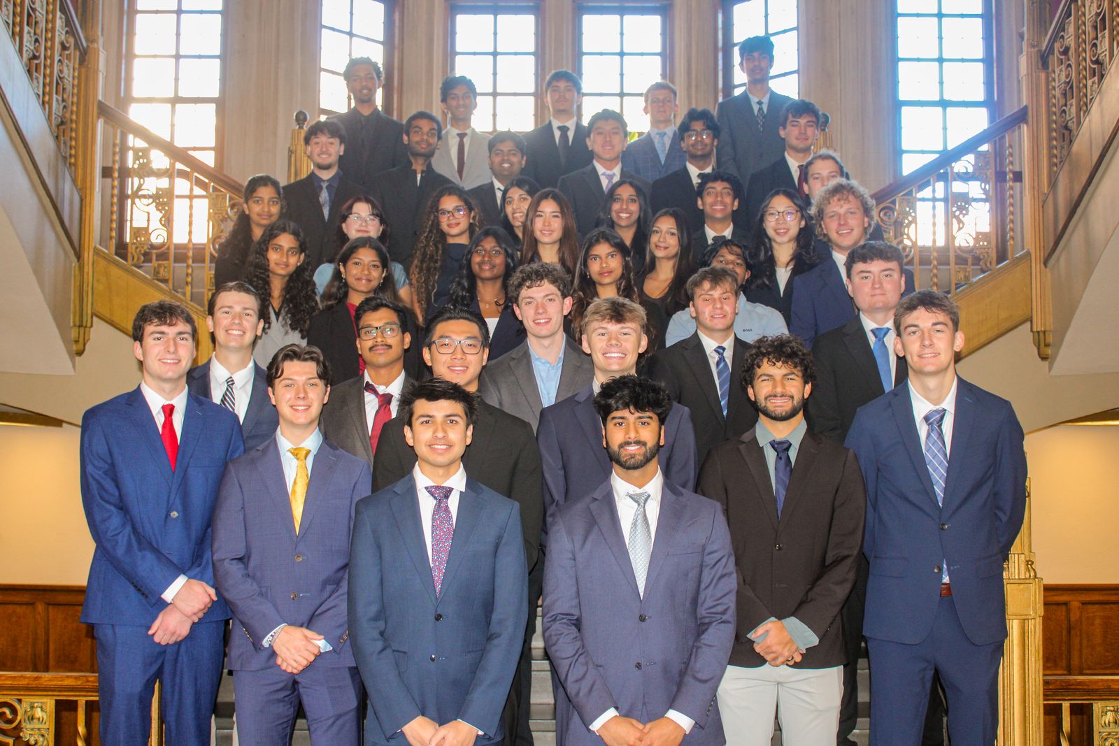 VITAL members posed together on a grand staircase in suits